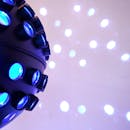 A vibrant blue disco ball with illuminated LED lights casting reflections on a surface.